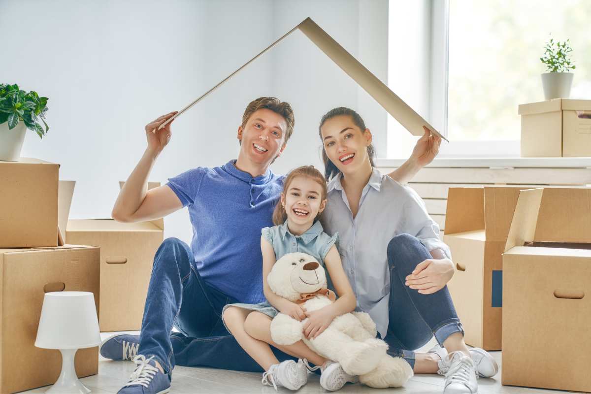 Famille composée d'un papa, d'une maman et d'une petite fille entourée de cartons lors de leur emménagement dans une nouvelle maison