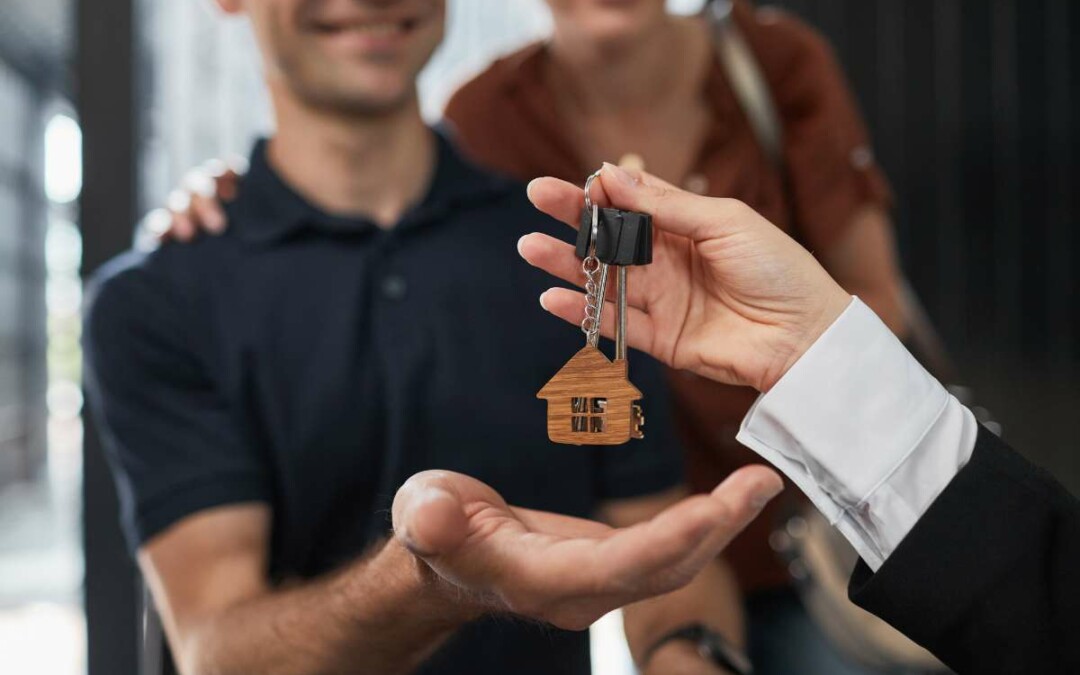 Main d'un agent immobilier tendant les clés d'une maison à ses nouveaux propriétaires
