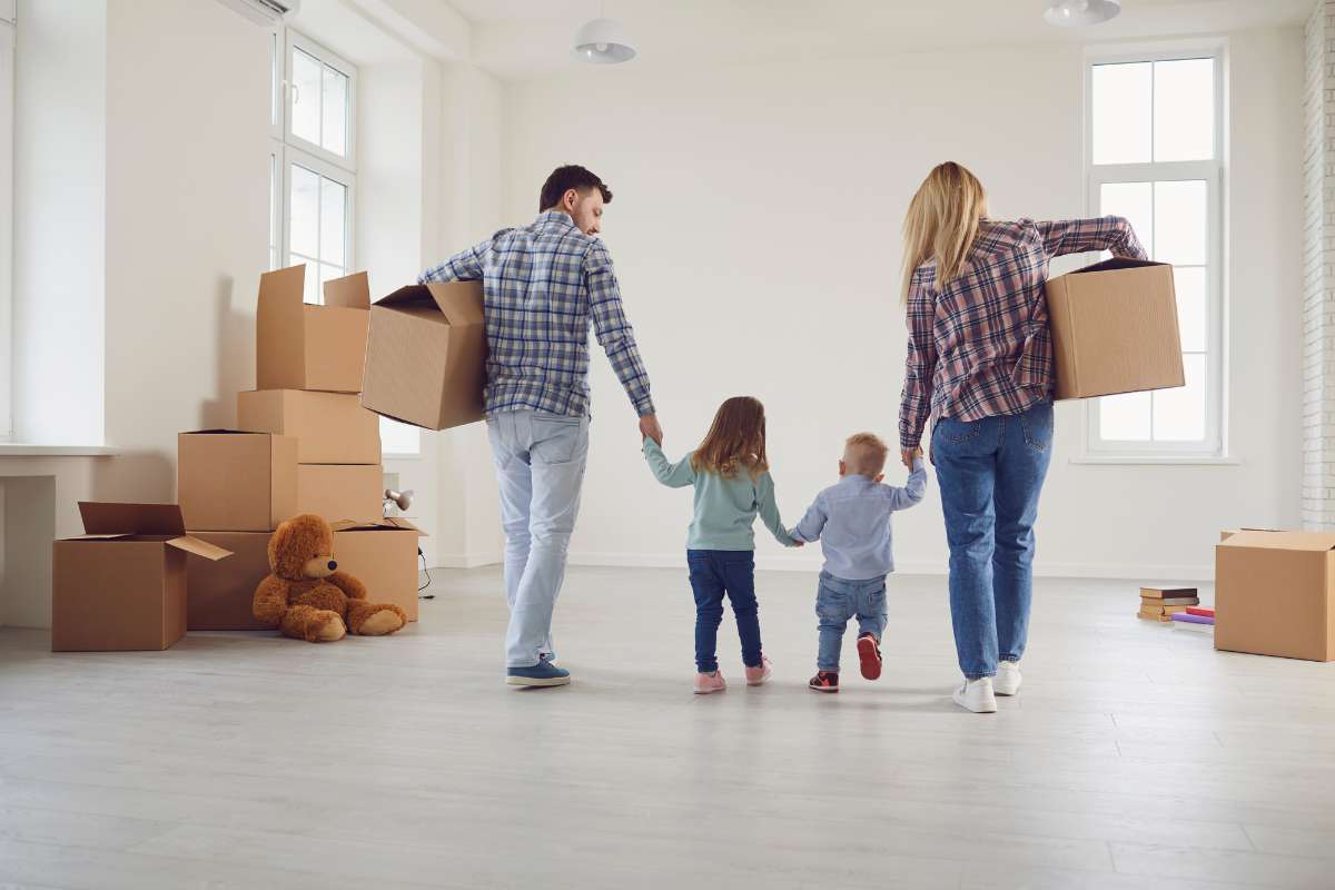 Papa et maman tenant la main d'une petite fille et d'un petit garçon avec des cartons de déménagement